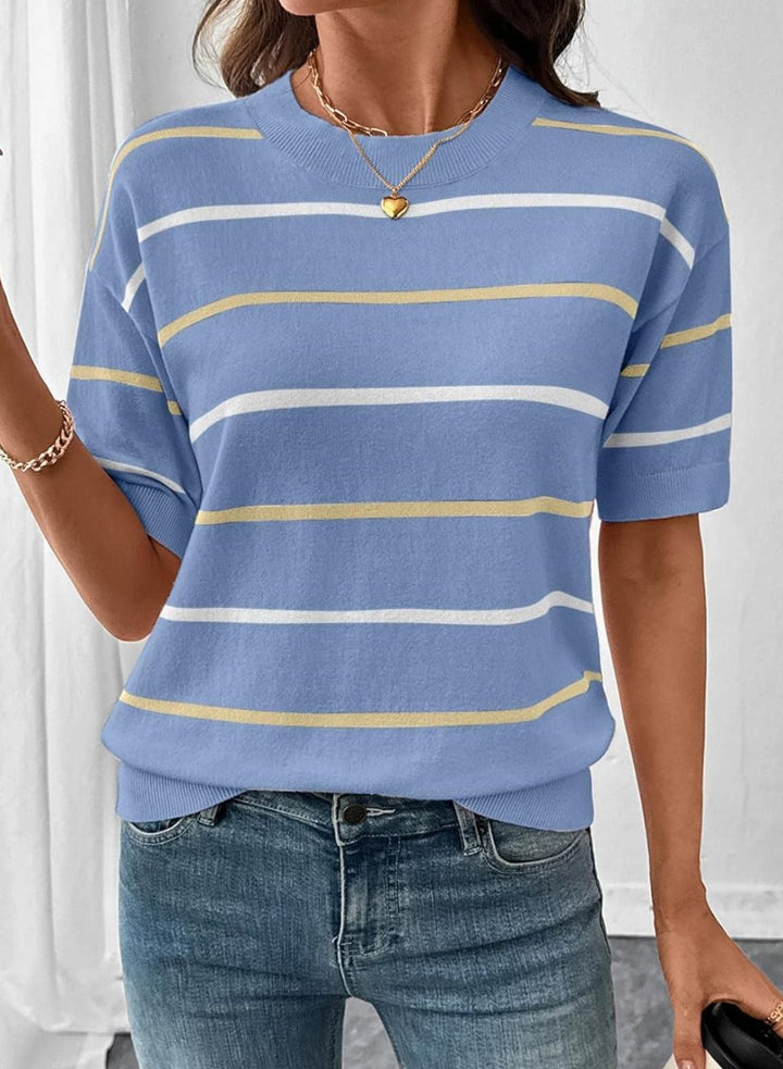 Person wearing a blue striped sweater and jeans against a white curtain background